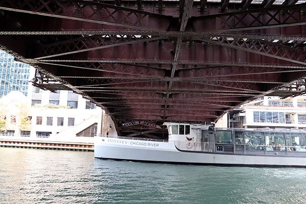 Boat named Odyssey Chicago River passes under bridge