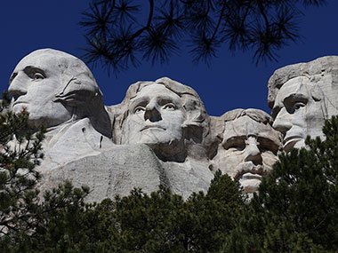 Mount Rushmore with trees below and single branch above