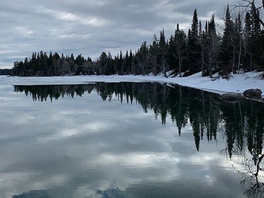 Trees and clouds reflect in lake