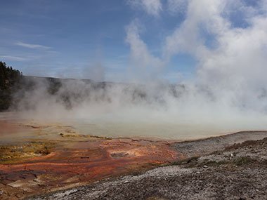 Steam rises above red colored pool