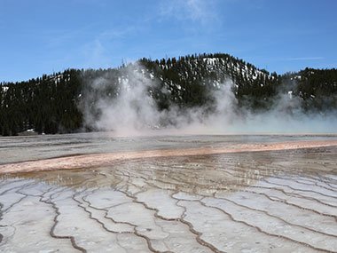 Steam rises with hills beyond