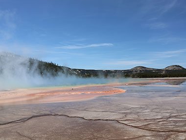 Yellowstone National Park as steam rises above red pool