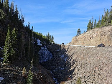 Car passes waterfall at Yellowstone National Park