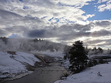 Yellowstone National Park - steam rises above geyser basin with stream in front