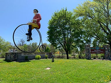 World's Largest Bicyclist in front of woods