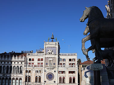 Horse statues in shade with clock tower in sunlight