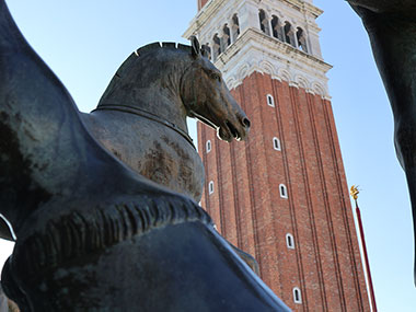 Closeup of horse statue in front of bell tower