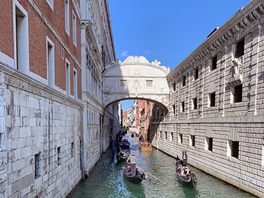 Two gondolas pass in front of the Bridge of Sighs