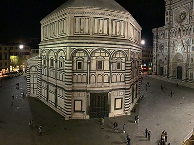 Baptistery at night with people walking down the street
