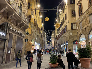 People walking down street under Christmas lights