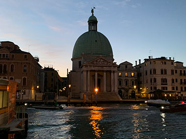 Sun starting to rise over the canal and buildings