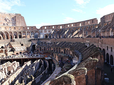 People walk on shaded side of the Colosseum