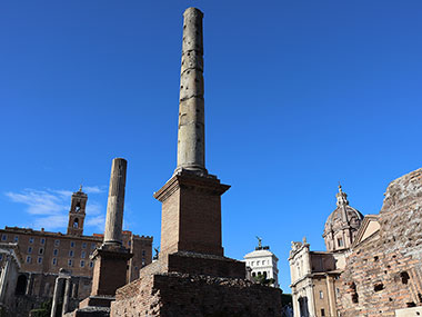 Two pillars in front of old buildings in Roman Forum