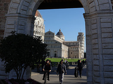 People walk under archway in Pisa