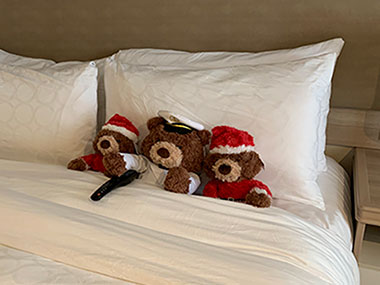 Three teddy bears sitting on bed