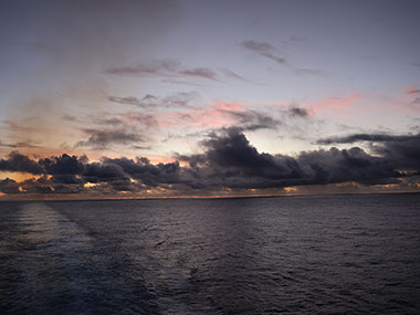 Sun rises behind ship