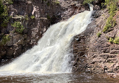 Waterfall crashes into river