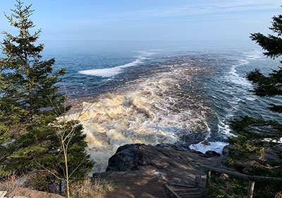 Cascade River flows past lake beyond trees