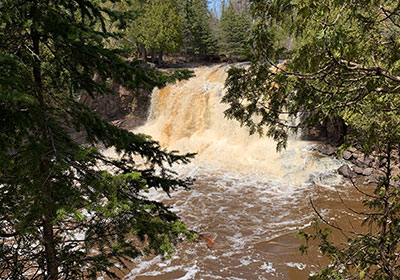 waterfall flows over rocks behind trees