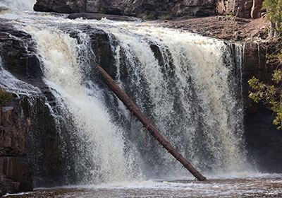 Closeup of log leaning on waterfall