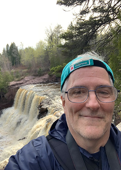 Pat smiles in front of waterfall