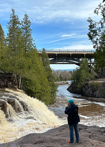 Pat takes picture from ledge in front of waterfall