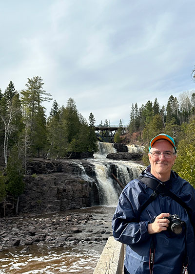 Pat holding camera in front of waterfall