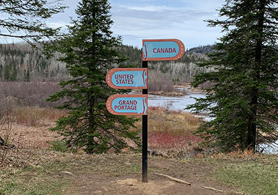 Directional sign pointing to Canada, United States, and Grand Portage