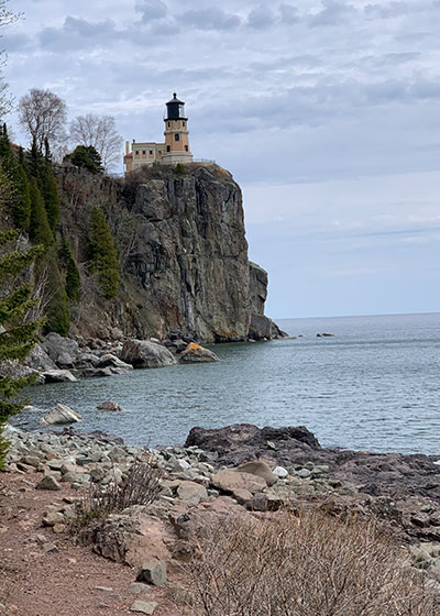 Rocks on beach with lighthouse beyond