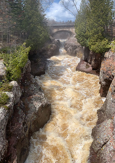 River flows under road on way to lake