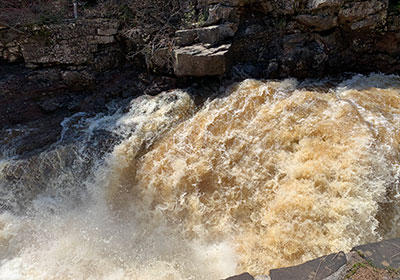 Restraining wall in front of river with water flowing past