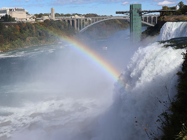 Rainbow with water flowing over Niagara Falls on American side