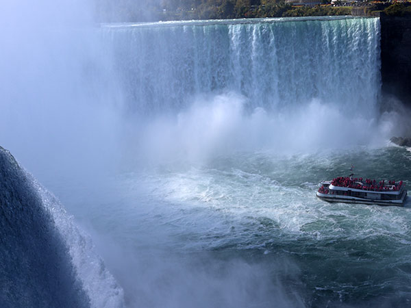 Close up of water flowing over Niagara Falls with boat from American side