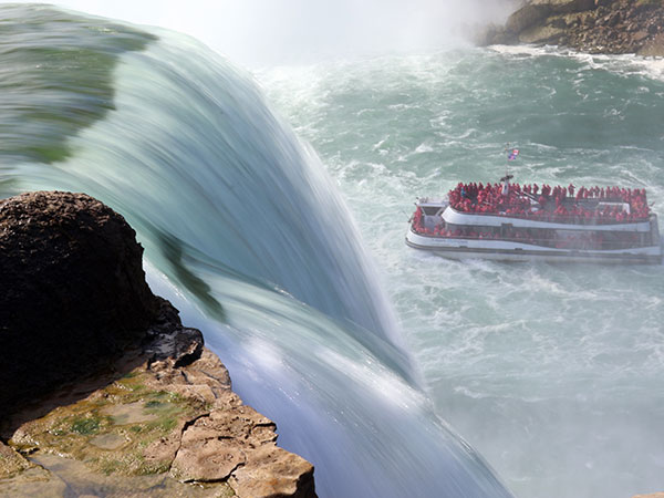 People in rain ponchos on sightseeing boat as it nears Niagara Falls