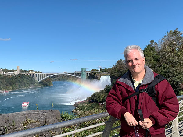 Pat with waterfall and wainbow behind him