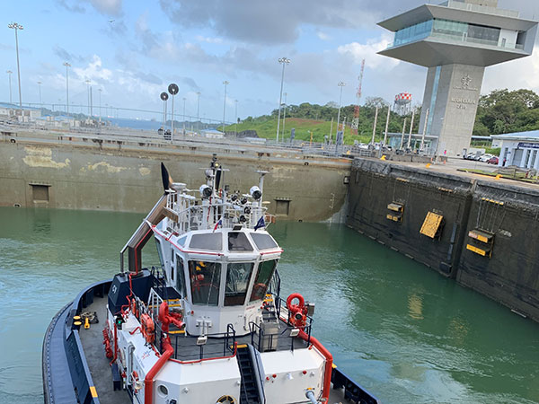 Tugboat pushes ship in Panama Canal with lock open